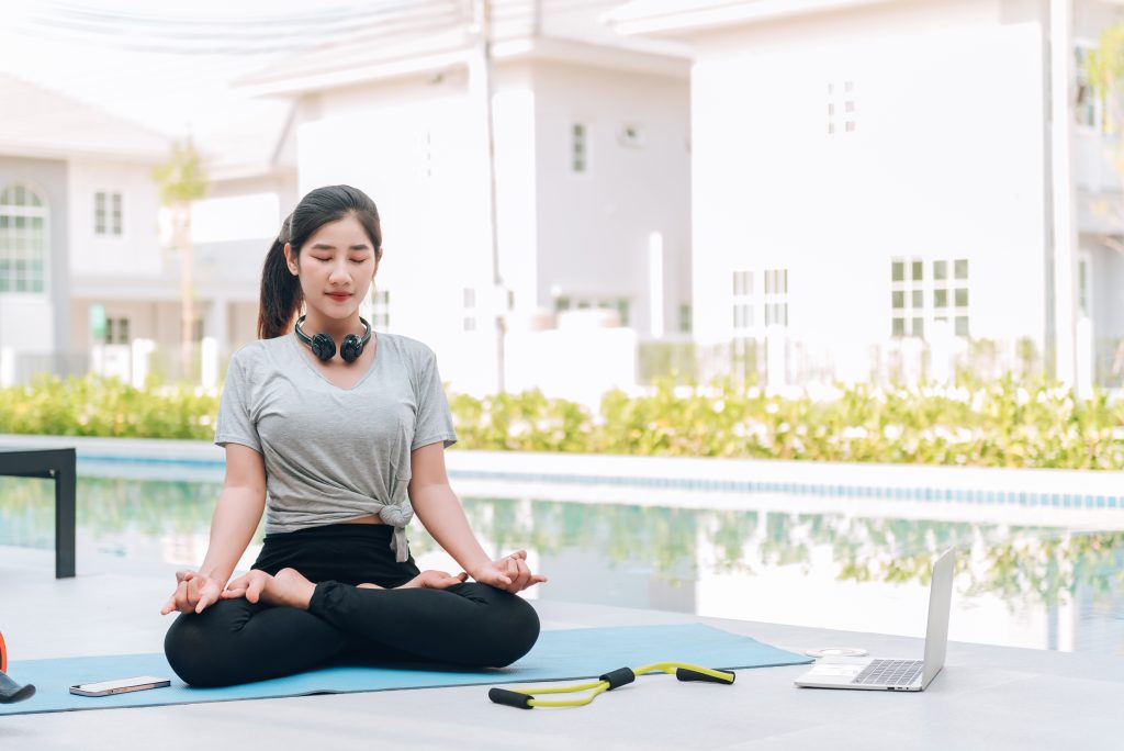 happy asian woman stretching exercise and yoga workout in the mo